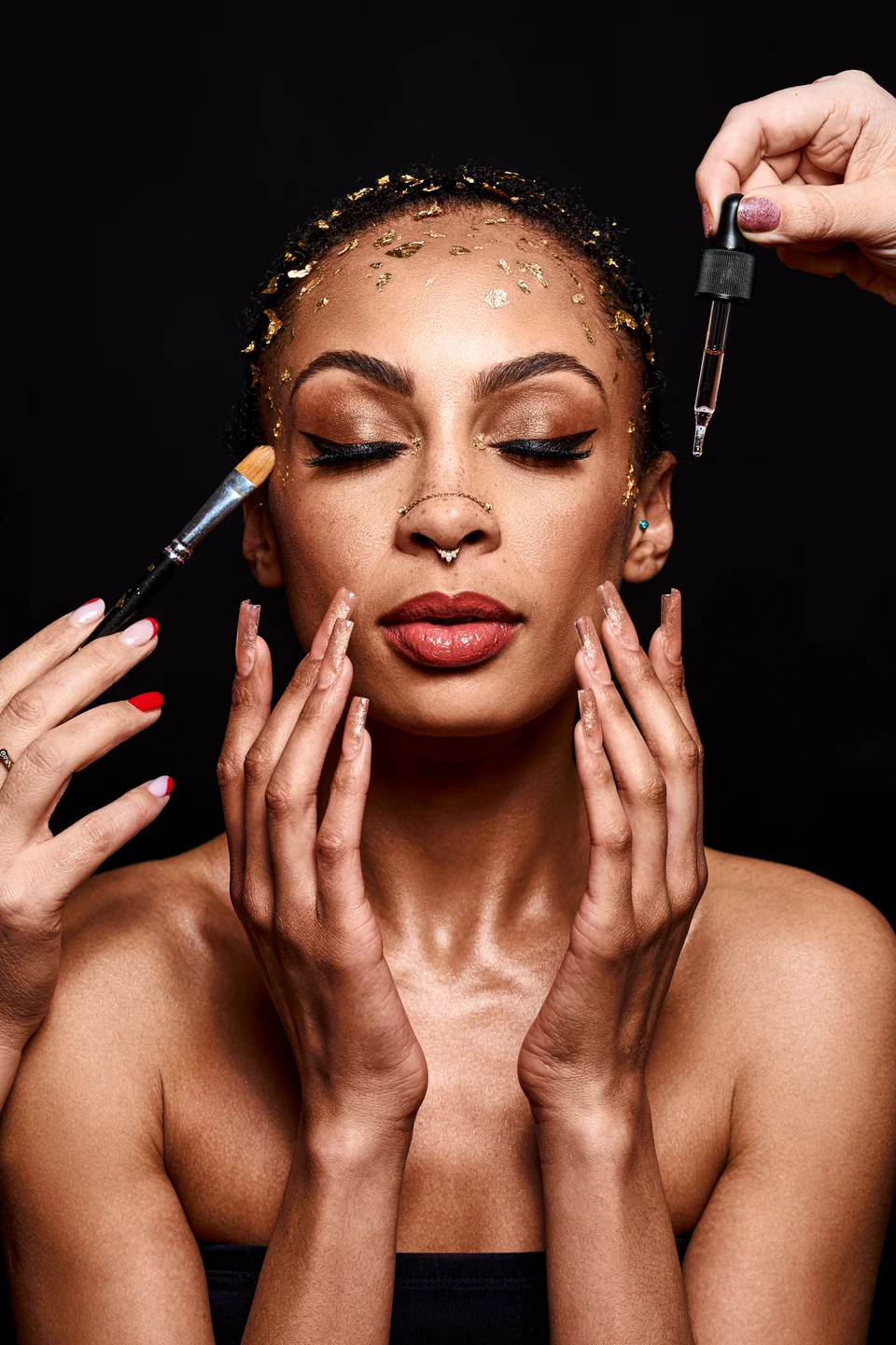 Portret beauty z płatkami złota, pędzlem do makijażu i pipetą