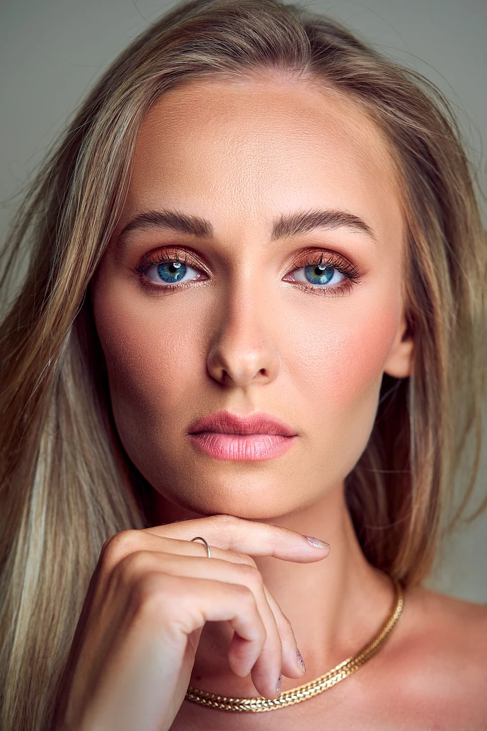 Portret beauty z bliska blondynki o niebieskich oczach z dłonią pod brodą