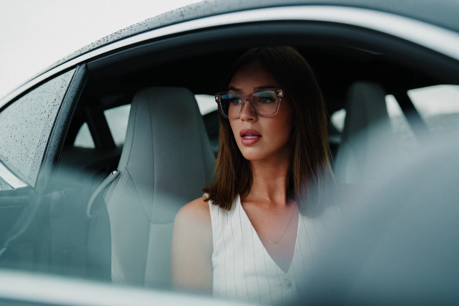 Cinematic portrait through a rain-speckled car window