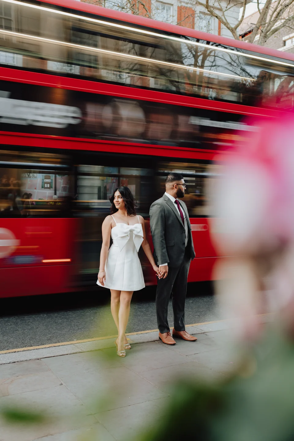 Couple beside a red bus in motion