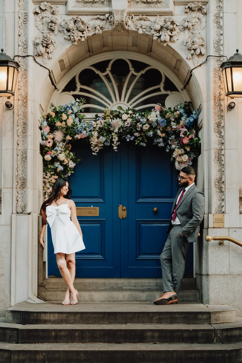 Couple at a blue doorway framed by flowers