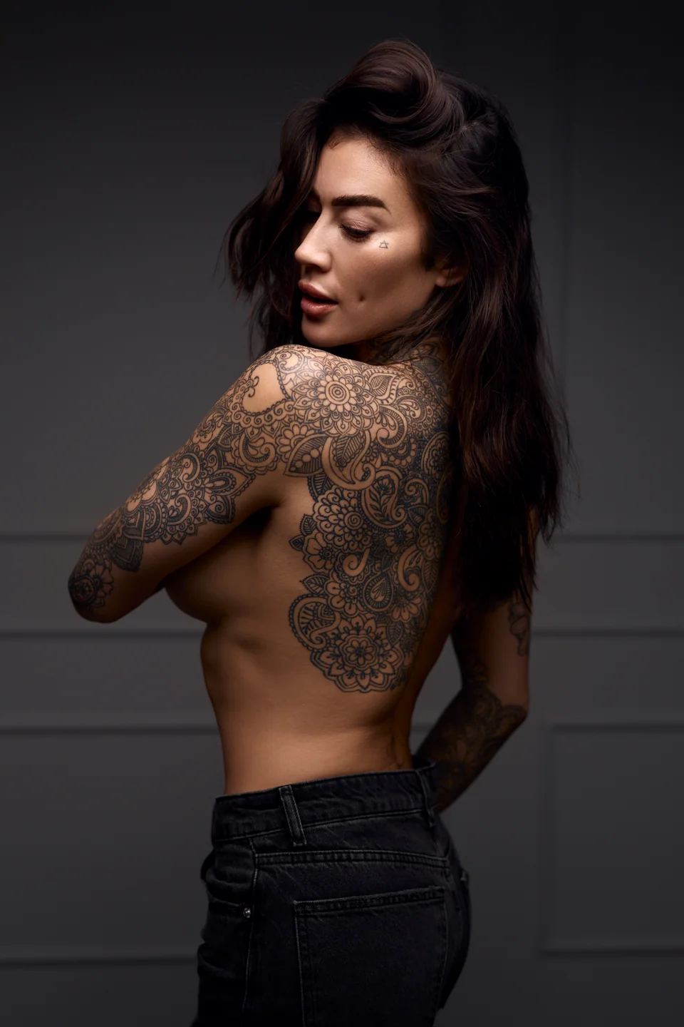 Portret ze spojrzeniem przez ramię i tatuażem na plecach